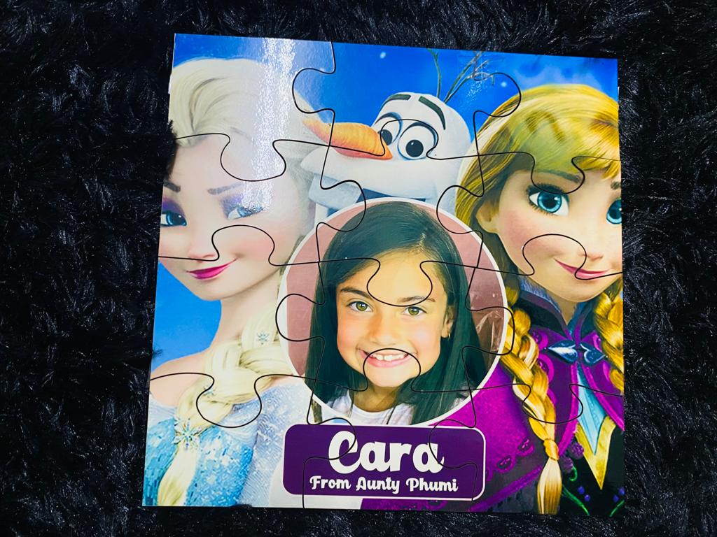 Children's puzzle with Frozen characters and a personalized name tag on a dark textured background