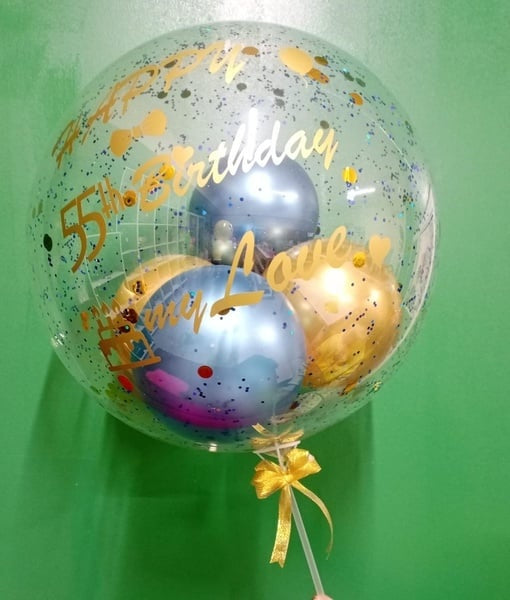 Clear bubble balloon with gold and blue text on a green background