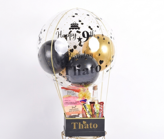 Decorative balloon basket with balloons and snacks on a white background