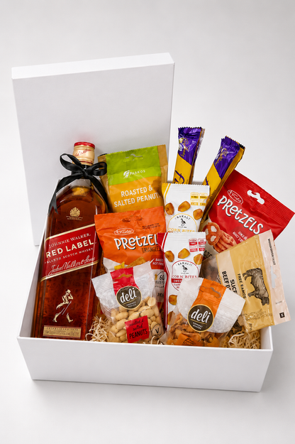 Gift basket with a bottle of Red Label whisky and various snacks in a white box.