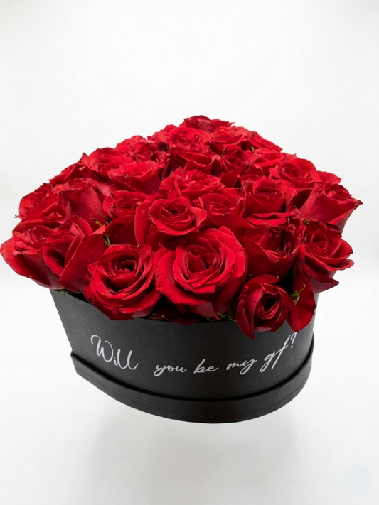 Box of red roses with 'Will you be my gift?' text on a white background