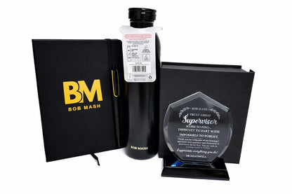Bottle of Bob Mash with a black notebook and an award on a white background