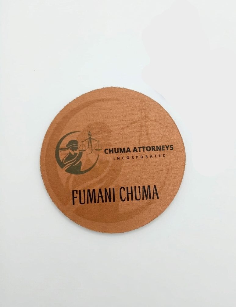 Wooden coaster and keychain with 'Chuma Attorneys' branding on a white background