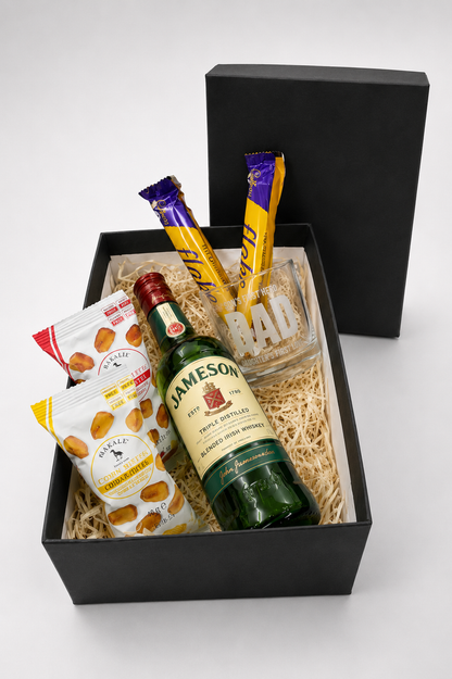 Gift basket with Jameson whiskey, snacks, and a glass on a white background