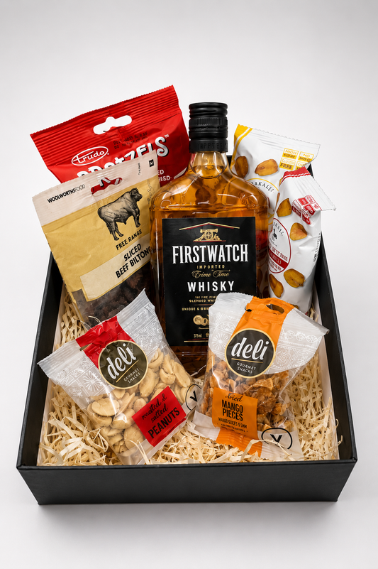 Gift basket with whisky, snacks, and deli items on a white background