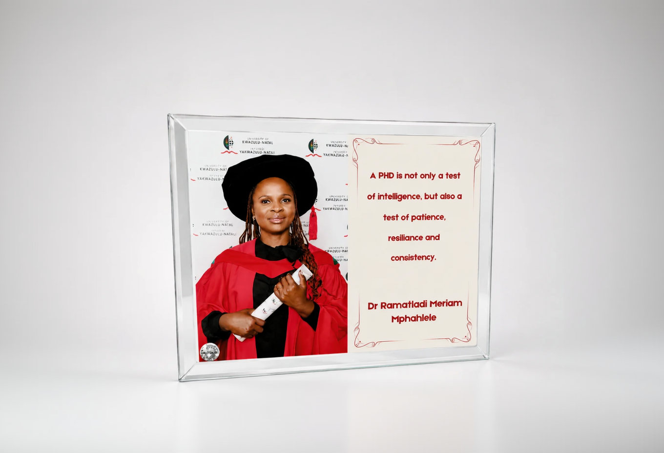 Person in graduation gown with framed quote on a white background