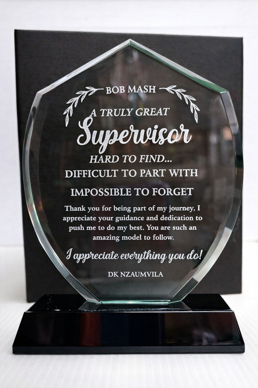 Glass award with engraved text on a black stand against a white background