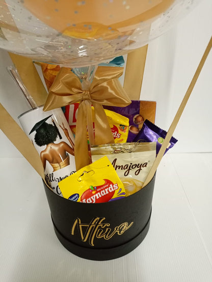 Gift basket with snacks and a tumbler on a white surface