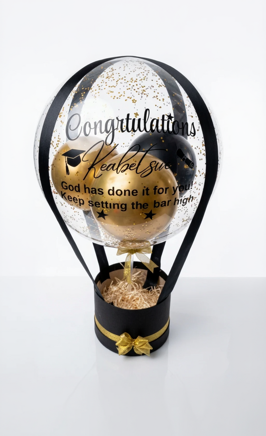 Graduation-themed decorative item with text inside a glass sphere on a white background