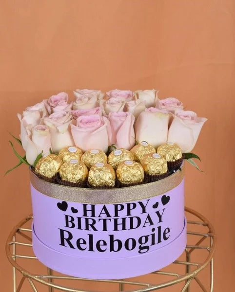 Birthday gift with roses and chocolates in a purple box on a gold stand against an orange background