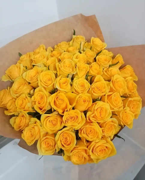 Bouquet of yellow roses wrapped in brown paper on a white background