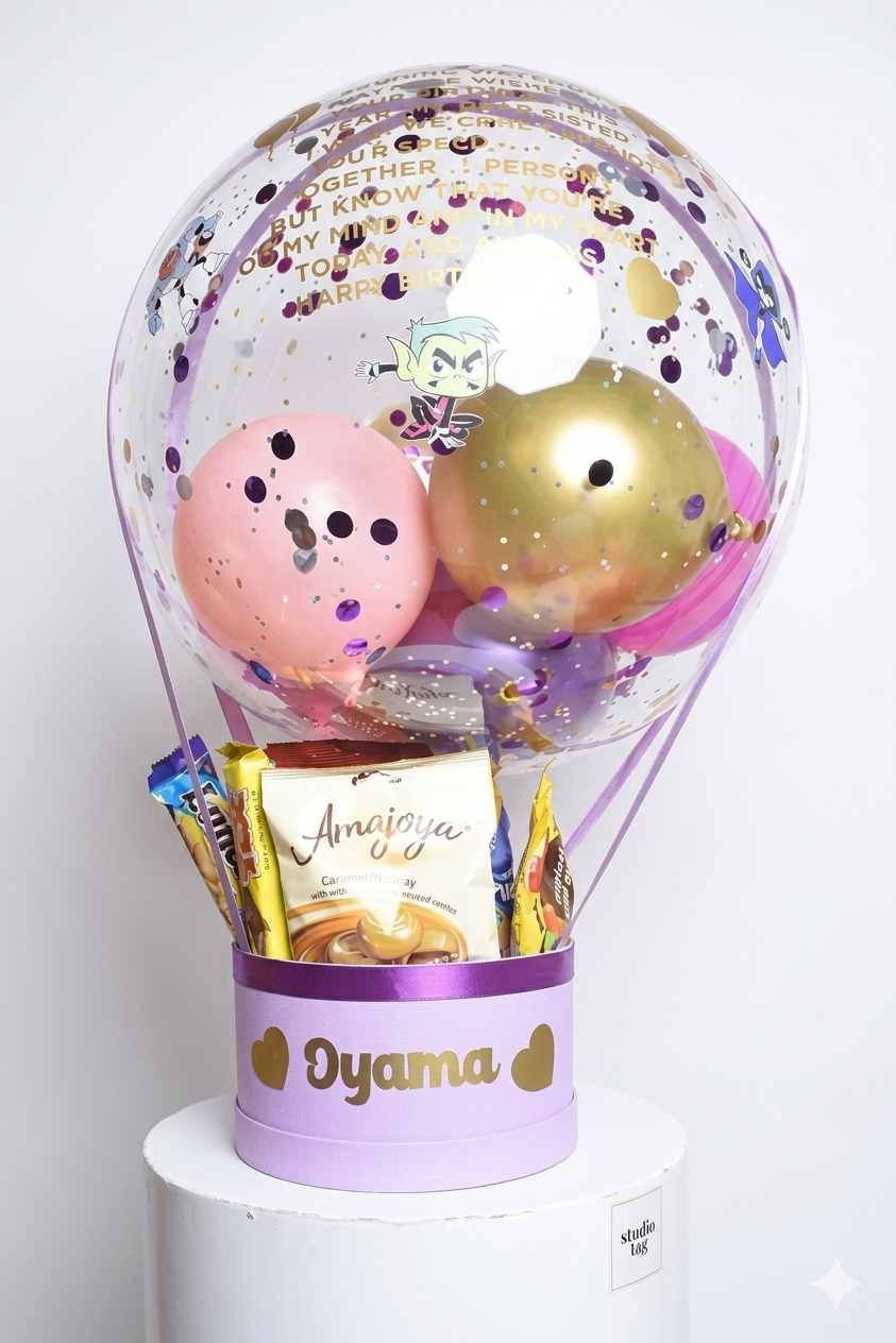 Decorative balloon with pink and gold balloons inside a transparent container, featuring a card and small items on a white background.