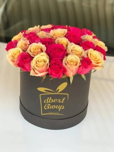 Box of pink and yellow roses with 'dbest Group' branding on a white surface.