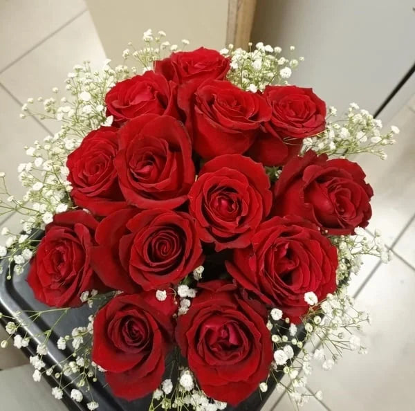 Bouquet of red roses with small white flowers on a tiled floor background