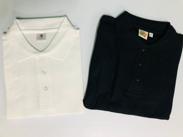 Folded white and black golf shirts on a light gray background