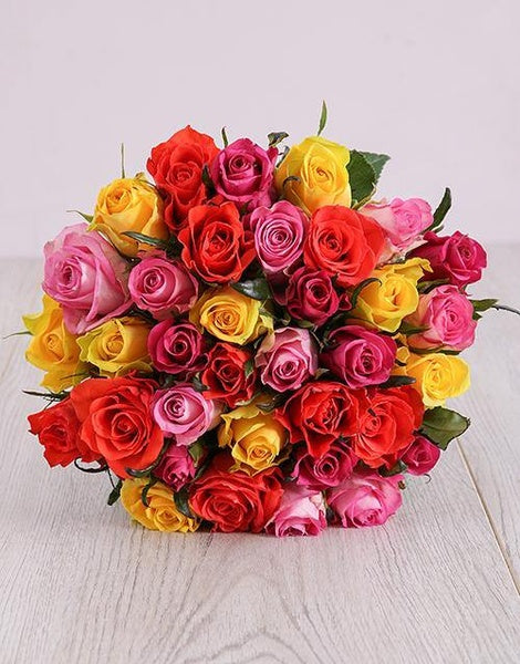 Bouquet of colorful roses on a light wooden surface