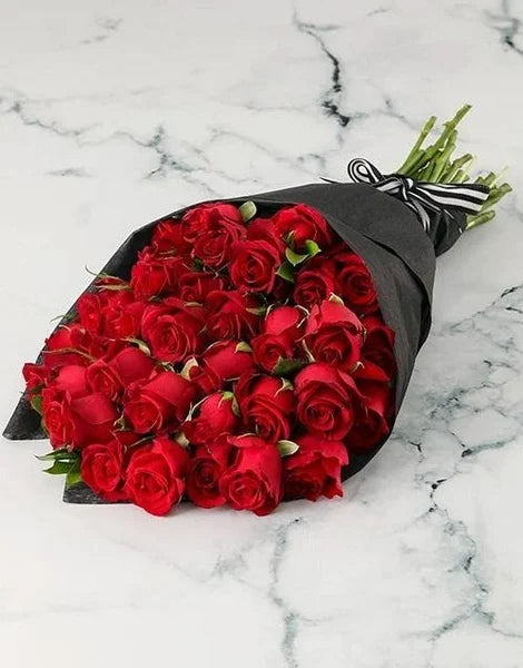 Bouquet of red roses wrapped in black paper on a marble surface