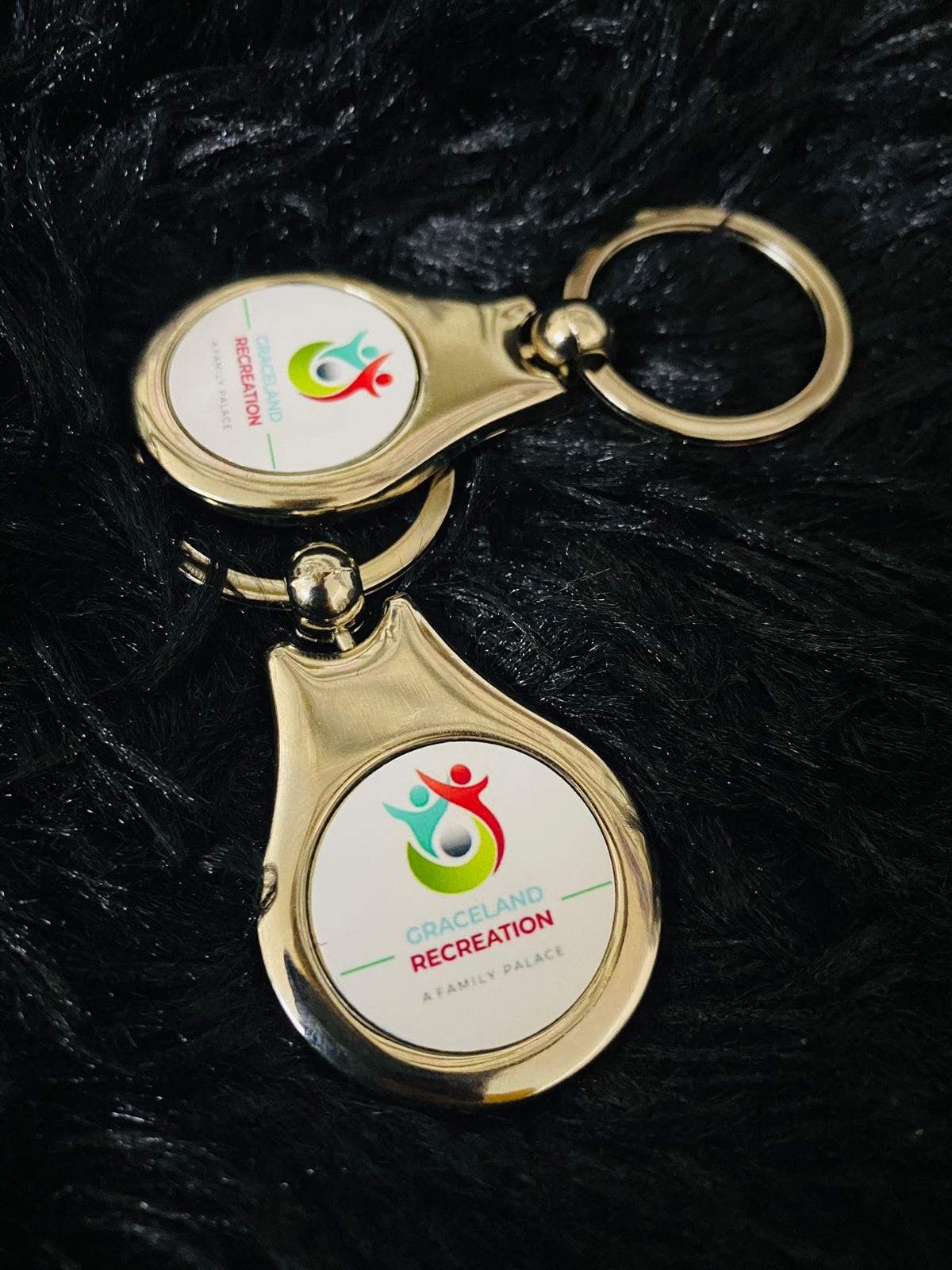 Gold keychain with a logo on a black textured background.  Gifting in Pretoria.