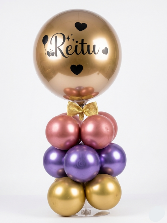 Decorative balloon arrangement with gold, pink, and purple balloons and a bow tie on a white background.