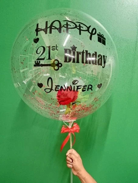 Clear balloon with 'Happy 21st Birthday Jennifer' text and a red rose, held against a green background.