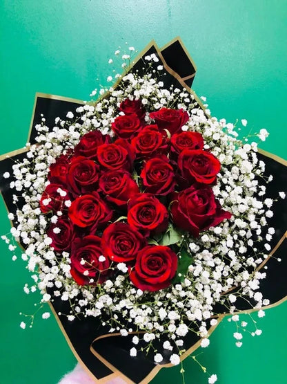Bouquet of red roses and gyp in a heart shape on a green background