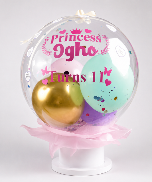 Clear balloon with gold and green balloons inside, featuring 'Princess Ogho Turns 11' text.
