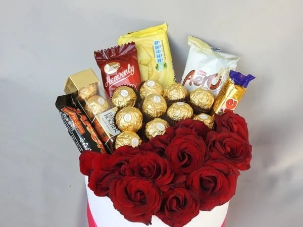 Bouquet of red roses with assorted chocolates on a gray background