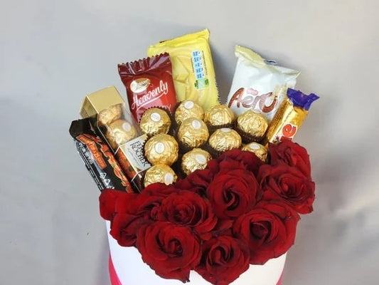 Bouquet of red roses with assorted chocolates on a gray background
