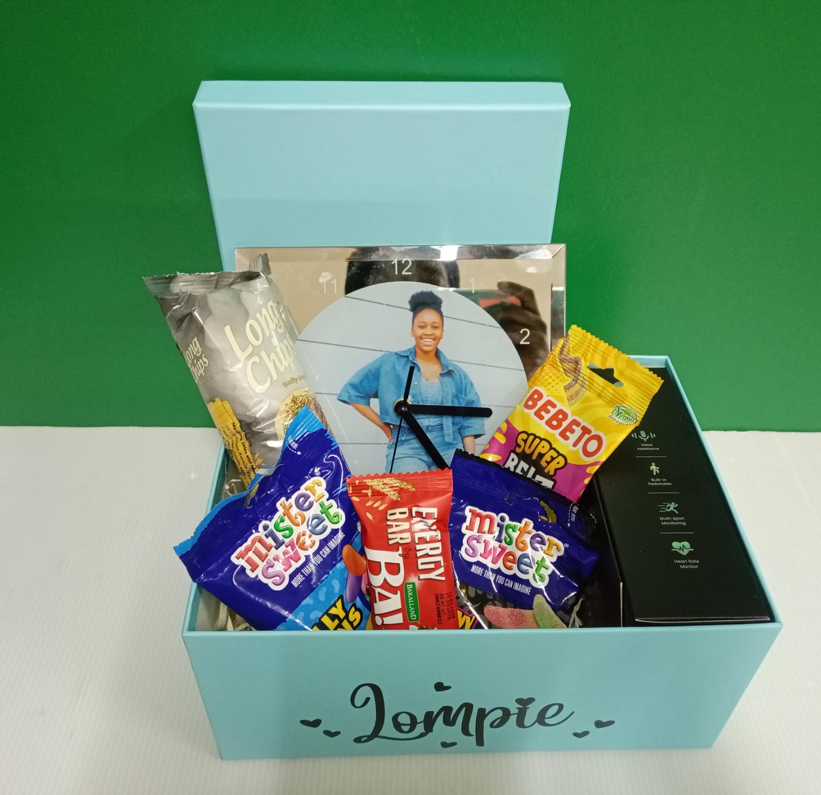 Gift box with snacks and a clock on a green background
