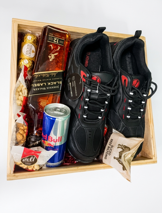 Gift box with black sneakers, alcohol, and snacks on a white background