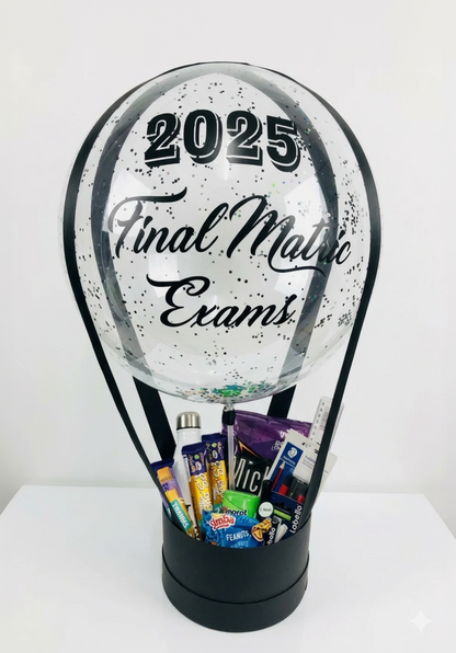 Clear snow globe with '2025 Final Matric Exams' text, filled with stationery and snacks.