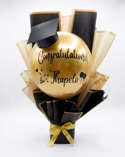 Gold balloon with 'Congratulations! Thapelo' text, wrapped in black and gold paper on a white background