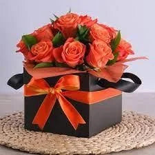 Floral arrangement in a box with an orange ribbon on a light background